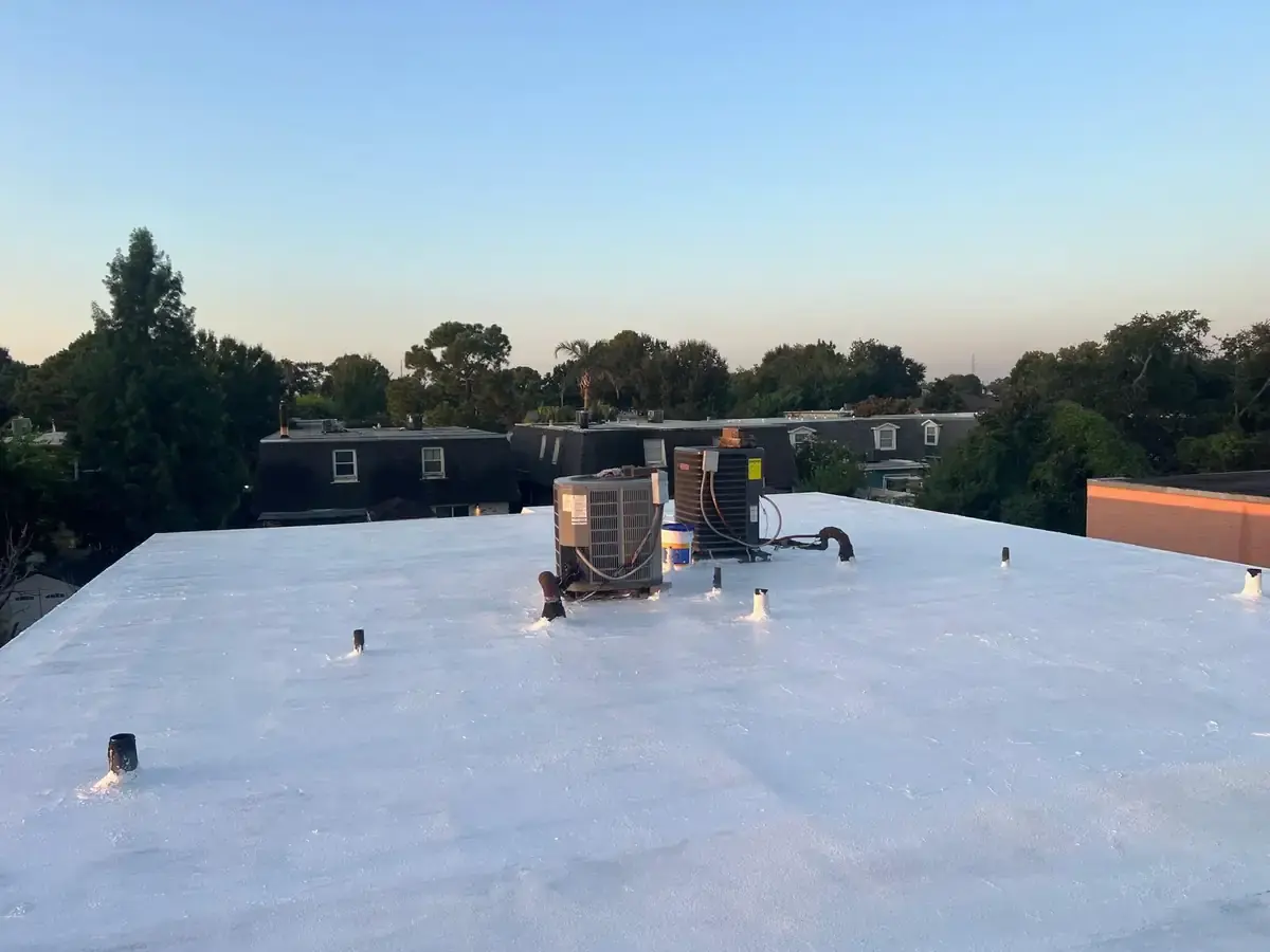 White-coated low-slope roof surrounding two rooftop air-conditioning units