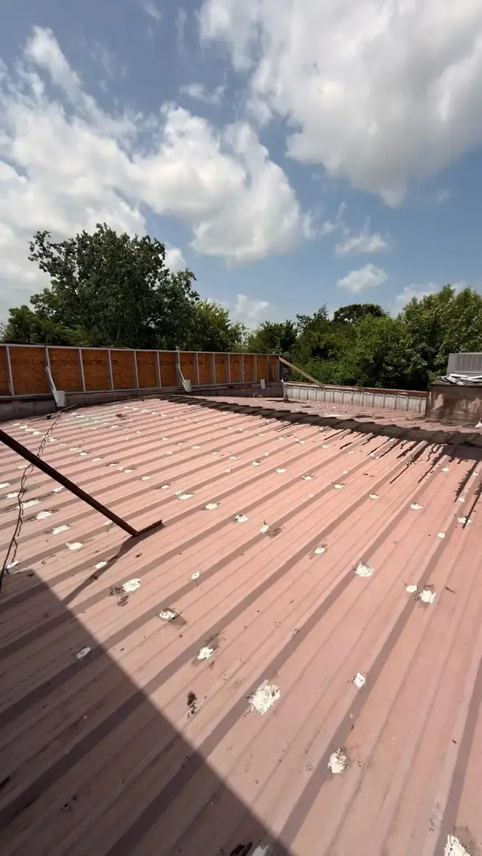 Red metal roof panels with light-colored treatment at rows of fasteners