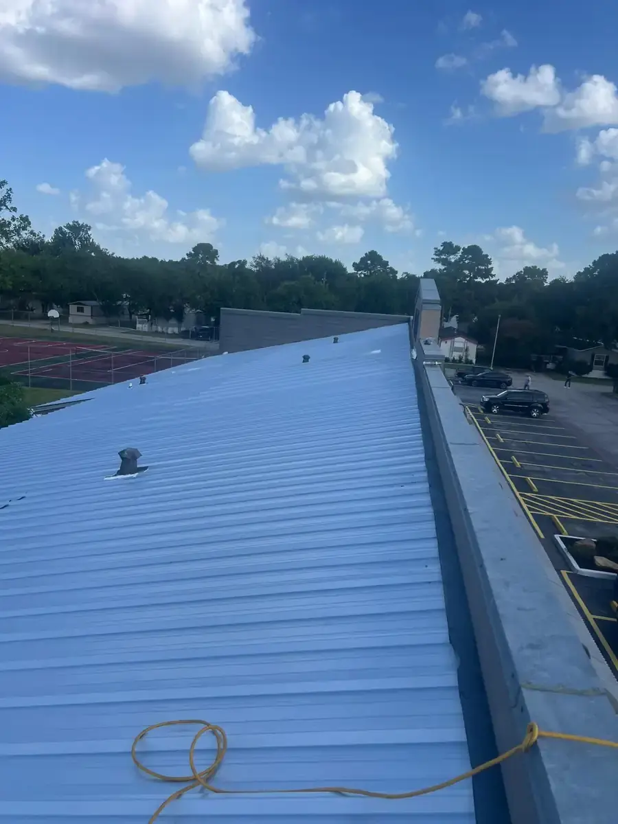 Light-colored metal roof panels installed along a slope with vent penetrations
