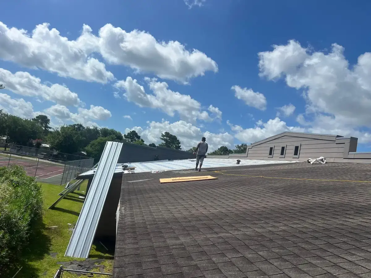 Roofing worker beside staged metal panels and a partially prepared roof