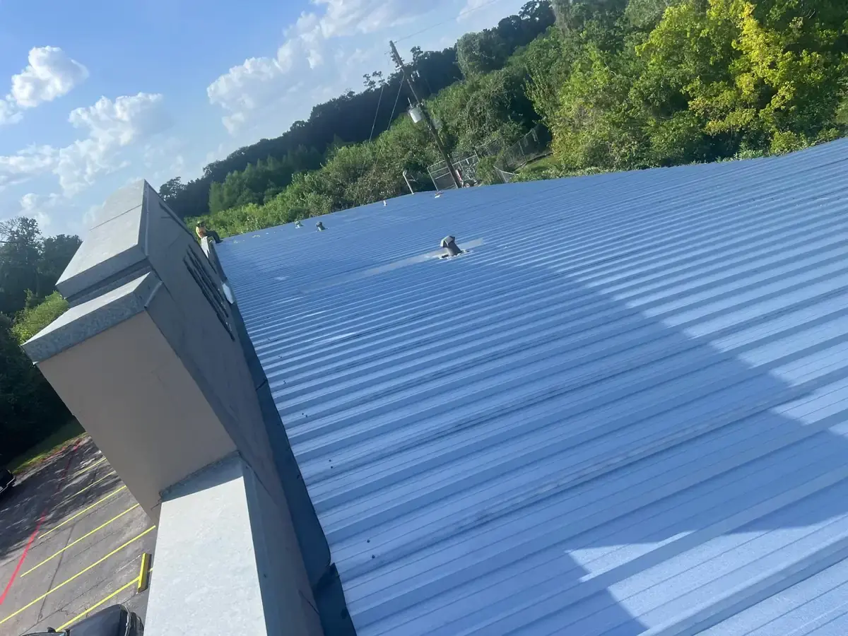 Wide view of light-colored metal roofing beside a raised roof wall