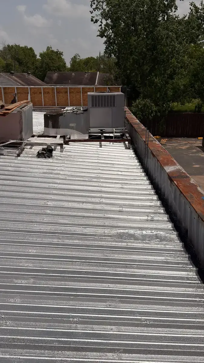 Silver-coated ribbed metal roofing around an air-conditioning unit