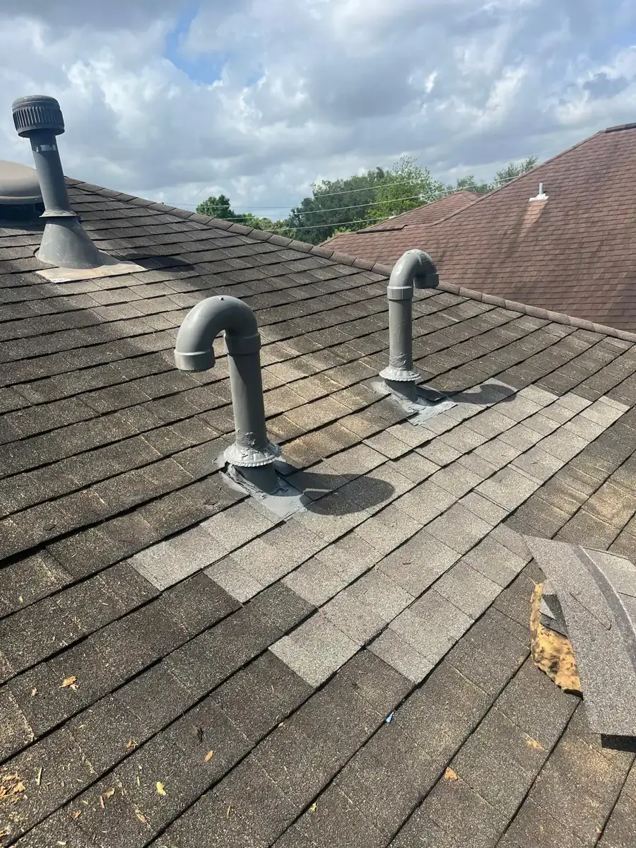 Shingle roof surface restored around two curved metal vent pipes