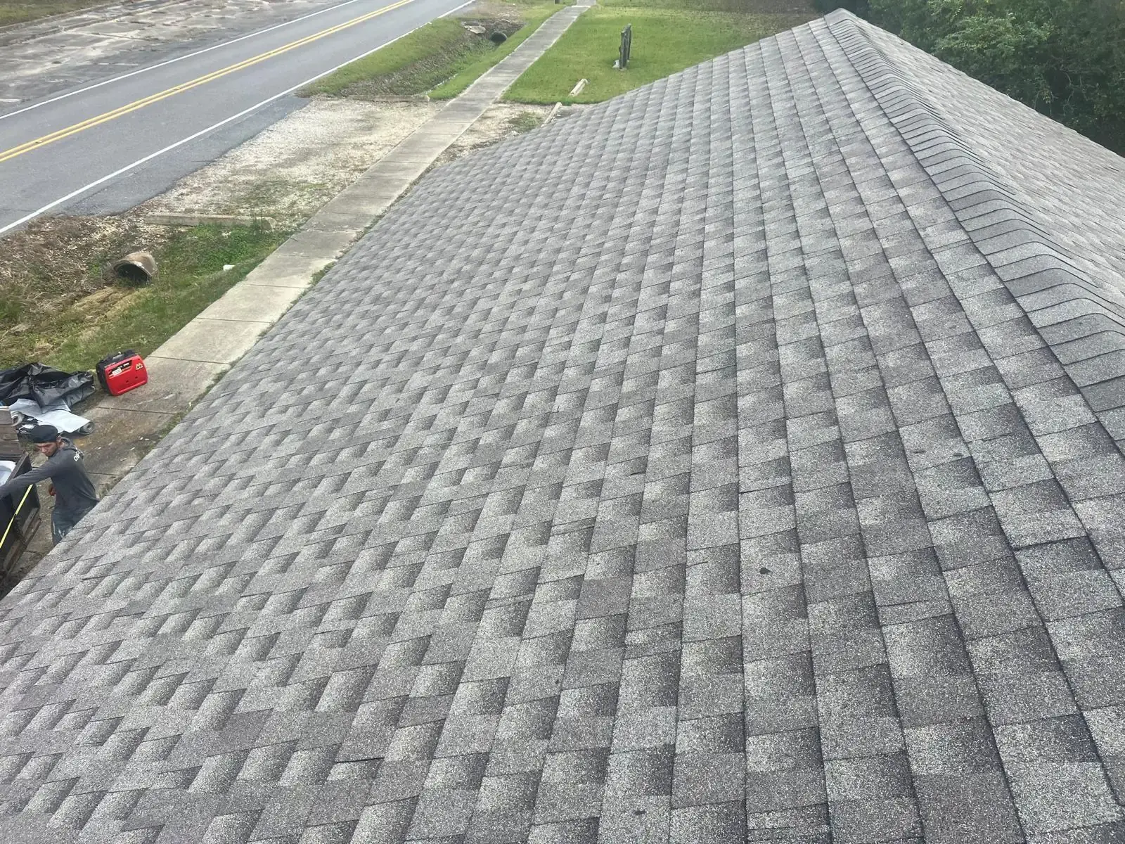 Gray architectural shingles covering a pitched roof with ridge-cap shingles