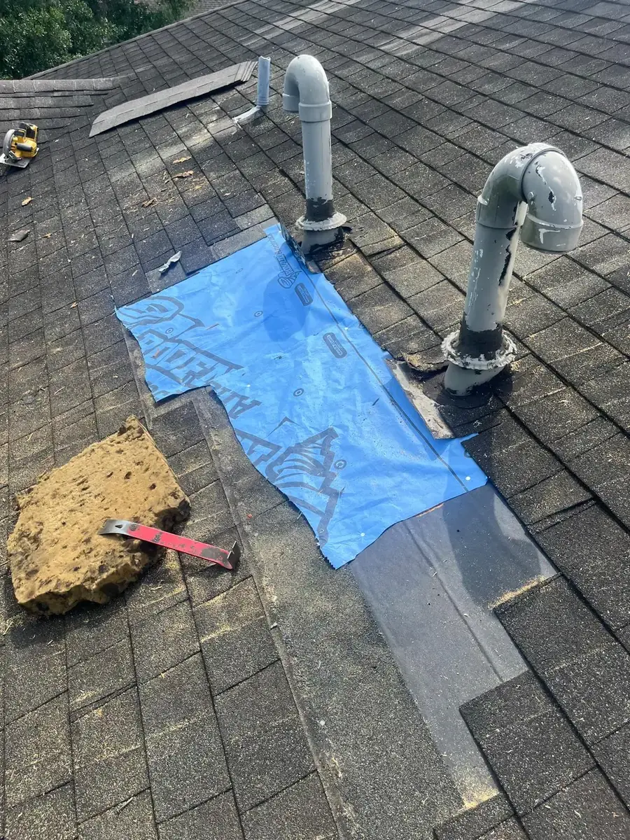 Blue underlayment covering a decking repair around roof pipes